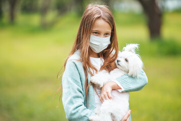 Little girl with dog wearing protective medical mask for prevent virus outdoors in the park