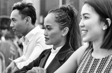 Three asian young friends standing outdoor in the city talking, smiling and enjoying city life