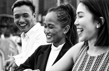 Three asian young friends standing outdoor in the city talking, smiling and enjoying city life