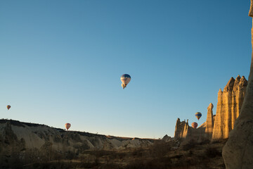 Fototapeta na wymiar Balloons flying in Cappadocia, Göreme at sunrise. Cappadocia is known around the world as one of the best places to fly with hot air balloons. Turkey.
