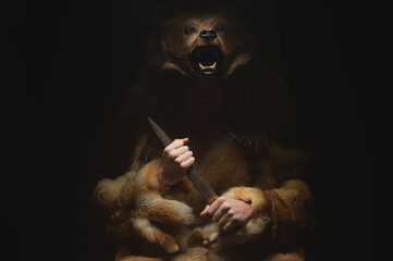 Low key portrait of a bearded war shaman in bearskin with an ancient ax in his hands. High quality...