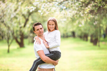 Fototapeta premium Family of father and daughter in blooming cherry garden