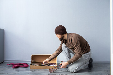 Fototapeta premium bearded man unpacks a box of furniture parts.