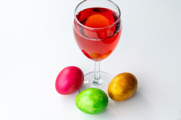 The glass of red wine or Cahors and Easter eggs on the table. View from above.