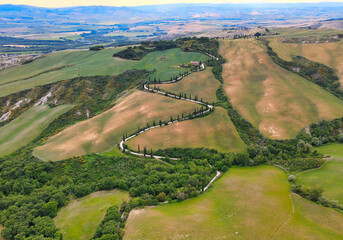 Aerial view of Monticchiello zigzag cypress road from drone in Tuscany, spring season