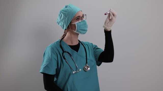 Female doctor examines a blood sample for the Corona virus - studio photography