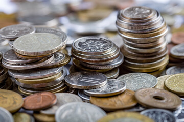 Various multi-colored coins of the currency of the whole world stacked on top of each other. The concept of banking, currency exchange, globalization, money, wealth