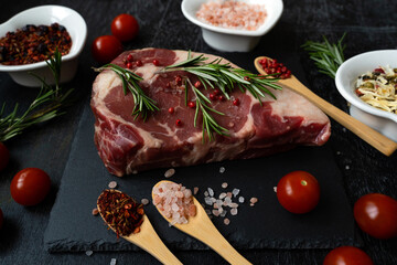 Ribeye raw piece of beef fillet on a slate board and spices for meat in spoons and heart shaped utensils. Cooking a dish. Everything for a barbecue. Macro photo