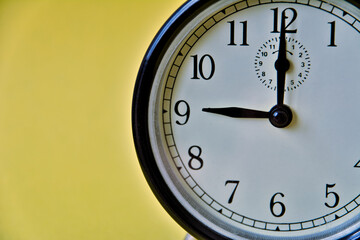 Shot of vintage retro analog clock on yellow background showing 9 o clock
