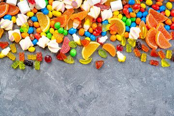 Sweets and candies background. Different candies, marshmallows, marmalade, yummi gummi scattered on the table. Top view.