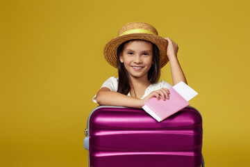 child with pink suitcase on yellow background.