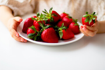  Cute little girl eating fresh strawberry in the kitchen. Healthy vitamin snack for kids. Ripe fresh berries. Harvest season. Natural vitamins .