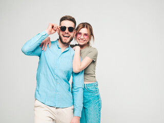 Smiling beautiful woman and her handsome boyfriend. Happy cheerful family having tender moments on grey background in studio.Pure cheerful models hugging.Embracing each other in sunglasses