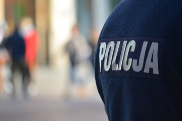 Polski policjant w niebieskim mundurze z napisem policja.  - obrazy, fototapety, plakaty