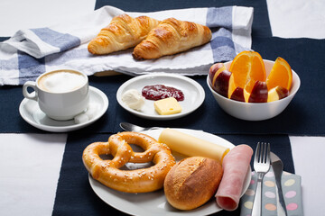 Bread, pretzel and croissants for breakfast with orange and apple and a cup of coffee