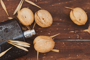 Fragrance for men in a black spray bottle on a brown wooden background with walnuts and maple seeds