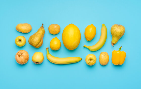 Yellow fruits and vegetables isolated on a blue background.