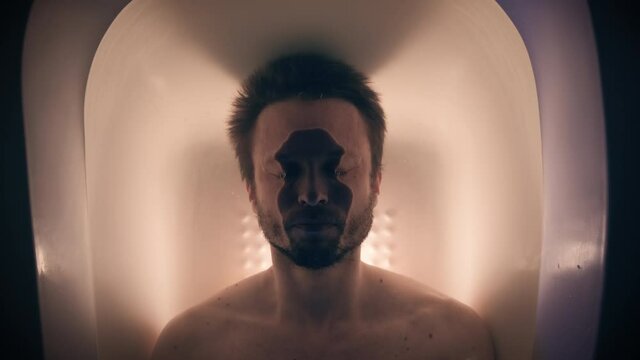 Adult male diving into water in the bath with color lighting