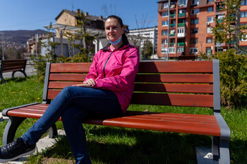 A young woman sits on the couch and waits for public transport. The time of the virus pandemic