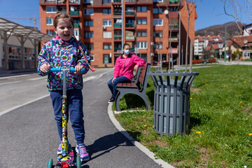 A little girl rides a scooter in an urban environment