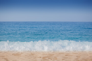 Closeup shoot of calm sea waves and foam on the sand beach.