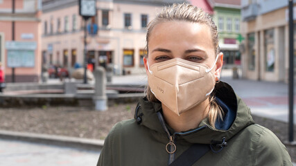 Girl with protective mask FFP2 on face against Coronavirus in city streets.