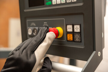 Emergency shutdown button in production. The CNC operator presses the emergency button on the control panel of the CNC machine. Place for text - obrazy, fototapety, plakaty