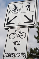 sign on a bicycle and pedestrian path, informing cyclists to yield to pedestrians