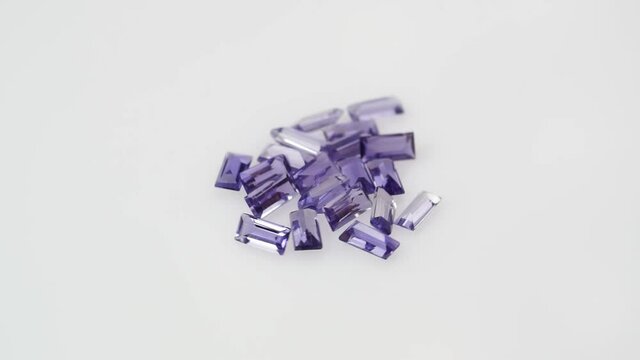 natural violet iolite gemstones on the white background on the turning table