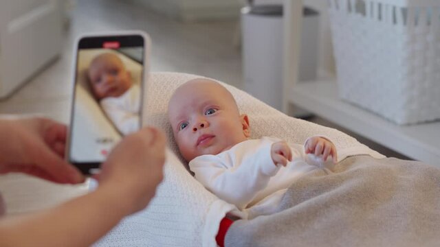 Mother recording video her newborn baby with smart phone at home. High quality 4k footage