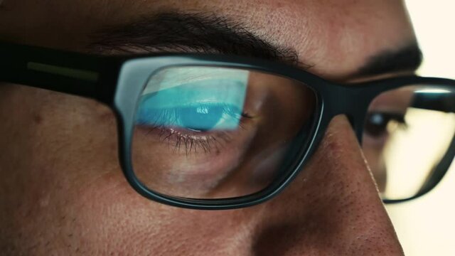 Macro on the eye of a software engineer who is working: the gaze focused on the screen,on the lens of the glasses we see the reflection.Clear and crystal clear image on the right lens. Selective focus