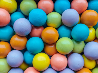 Background from multicolored bright small wooden balls of blue, yellow, red, lilac and green colors. A beautiful summer bright background for your projects..