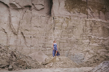 hippie woman in a gray dress stands on a cave landscape