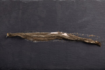 Completely rotten yellow bean pod placed on black slate