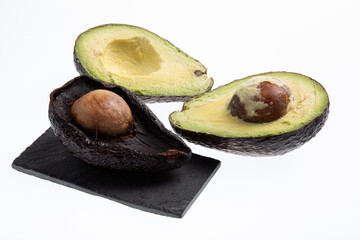 Fresh and ripe avocado next to rotting avocado cut in half with seed visible isolated on white