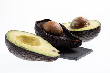 Fresh and ripe avocado next to rotting avocado cut in half with seed visible isolated on white