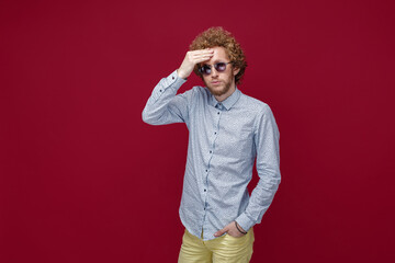 Portrait of elegant young man in sunglasses on red background