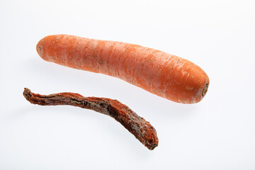 Fresh an ripe carrot next to one rotting carrot isolated on white