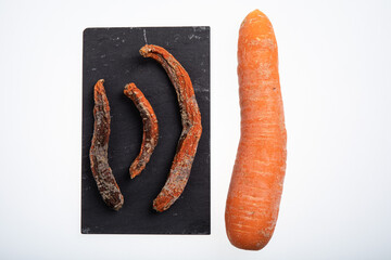 Fresh an ripe carrot next to three rotting carrots isolated on white