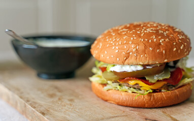 Rustic handmade hamburger with sauce on the table.