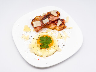breakfast with fried egg and fried bacon decorated with parmegiano cheese and parsley