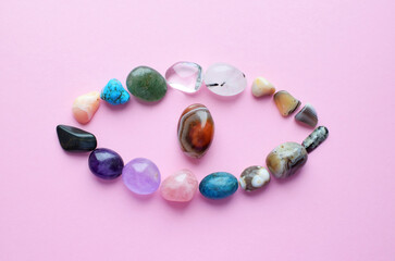 The eye is lined with natural minerals. Semiprecious stones of different colors, raw and processed. Amethyst, rose quartz, agate, apatite, aventurine on a pink background.