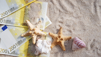 dollar bills on the sand. starfish and a string of pearls on the beach. 