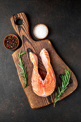 raw salmon steak with spices on a stone background