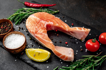 raw salmon steak with spices on a stone background with copy space for your text