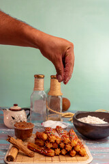 Man's hand drizzling sugar over typical Spanish churros with guava arequipe coated in colored sparks