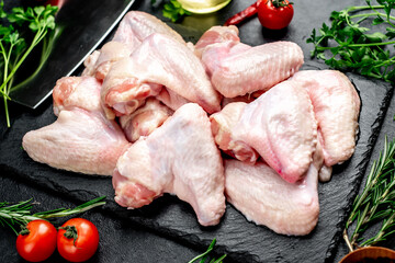 raw chicken wings with spices on a stone background