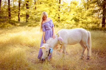 Woman in purple dress hugging white unicorn horse. Dreams come t