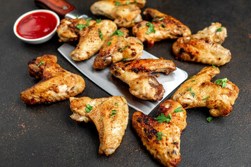 grilled chicken wings with spices on a knife on a stone background