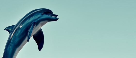 The figure of a dolphin in an amusement park against the blue sky. Theme of free time in weekend. Dolphin figurine